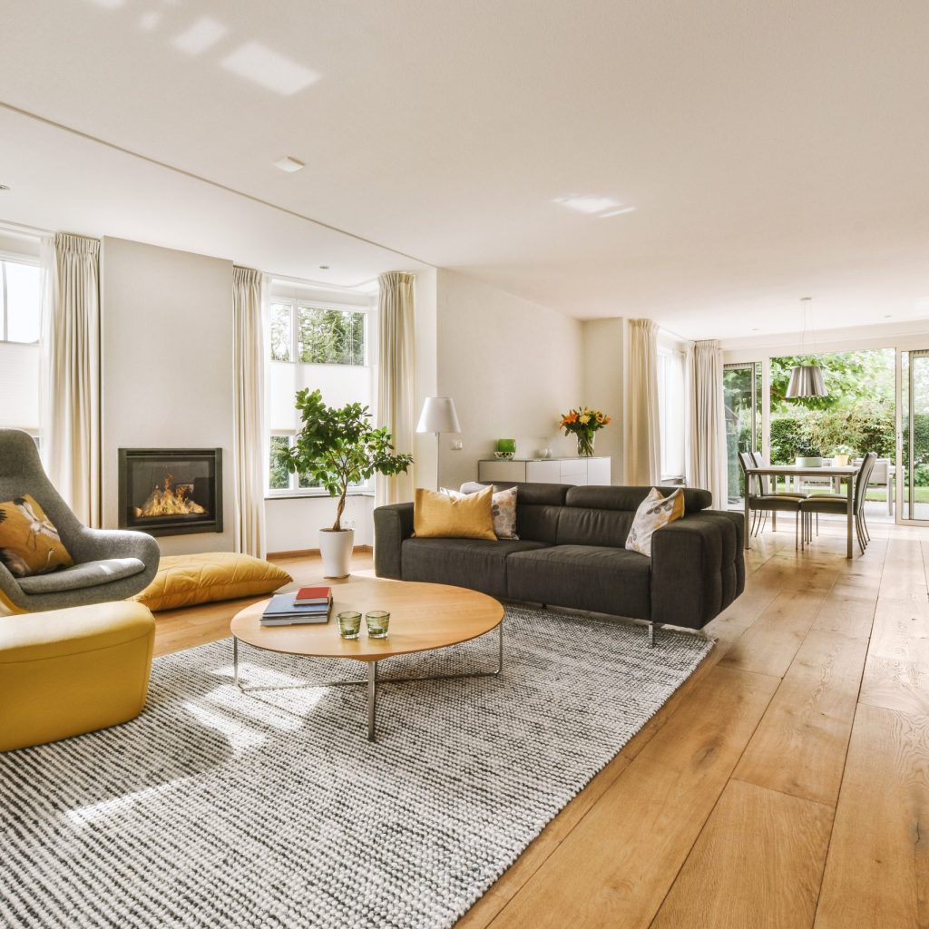 Contemporary minimalist style interior design of light studio apartment with wooden table and chairs in dining zone between open kitchen and living room with white walls and parquet floor